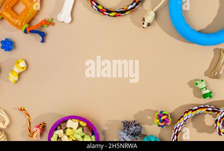 Verschiedene bunte Tierpflegezubehör: Schale, Knochen, Kugeln, Snacks, Maus auf beigem Hintergrund. Gummi- und Textilzubehör für Hunde und Katzen. Stockfoto