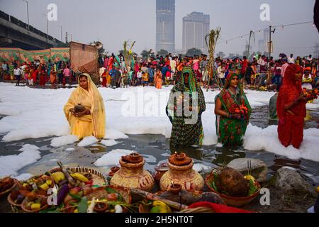 Okhla, Indien. November 2021. Eifrige Anhänger, die mit einigen Opfergaben den sonnengott anbeten, während sie inmitten der giftigen Schaumstoffe stehen, die den Yamuna-Fluss während des hinduistischen religiösen Festivals bedecken.Chhath Puja ist der Sonnengottheit und Shashti Devi (Chhathi Maiya) gewidmet. Sie für die Erfolge des Lebens auf der Erde zu danken und um bestimmte Wünsche zu erbitten. Dieses Fest wird von Biharis zusammen mit ihrer Diaspora gefeiert. Kredit: SOPA Images Limited/Alamy Live Nachrichten Stockfoto