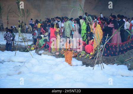 Okhla, Indien. November 2021. Eine eifrige Anhängerin sah den sonnengott anbeten, als sie inmitten der giftigen Schaumstoffe steht, die den Yamuna-Fluss während des hinduistischen religiösen Festivals bedecken.Chhath Puja ist der Sonnengottheit und Shashthi Devi (Chhathi Maiya) gewidmet. Sie für die Erfolge des Lebens auf der Erde zu danken und um bestimmte Wünsche zu erbitten. Dieses Fest wird von Biharis zusammen mit ihrer Diaspora gefeiert. Kredit: SOPA Images Limited/Alamy Live Nachrichten Stockfoto