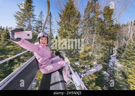 Skiurlaub - Frau Skifahrerin im Skilift macht Selfie Foto oder Video mit dem Telefon. Ski Winterurlaub Konzept. Skifahren auf Schneehängen in den Bergen Stockfoto