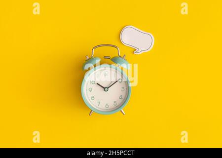 Wecker und Sprechblase aus Papier mit Platz für Text auf gelbem Hintergrund Stockfoto