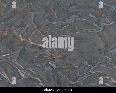 Nahaufnahme eines glatten Musters im feuchten braunen Sand am Long Beach in der Nähe von Tofino im Pacific Rim National Park auf Vancouver Island, BC, Kanada. Stockfoto