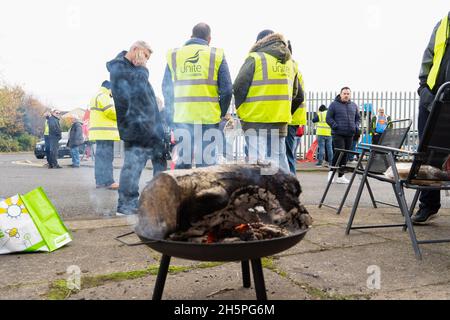 Stockton-on-Tees, Großbritannien. November 2021. Ein Feuer brennt, als streikende Busfahrer während des Streiks auf der Streiklinie vor ihrem Depot plaudern.erster Tag der Busfahrer für die Streikaktion von Stagecoach North East in Stockton, nachdem Gespräche zwischen Unite the Union und dem Unternehmen zusammenbrachen. In Stockton-on-Tees und Hartlepool wurden Streiks abgehalten, nachdem die Gewerkschaft sagte, dass die Mitarbeiter weniger bezahlt wurden als die Kollegen in anderen Teilen der Region. (Bild: © Jason Brown/SOPA Images via ZUMA Press Wire) Stockfoto