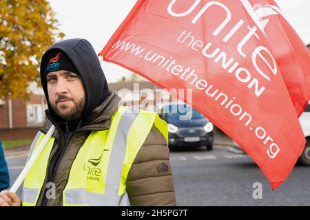 Stockton-on-Tees, Großbritannien. November 2021. Ein Busfahrer steht während des Streiks auf einer Streikschnur mit einer Gewerkschaftsflagge.erster Tag der Busfahrer für die Streikaktion von Stagecoach North East in Stockton, nachdem Gespräche zwischen Unite the Union und dem Unternehmen zusammenbrachen. In Stockton-on-Tees und Hartlepool wurden Streiks abgehalten, nachdem die Gewerkschaft sagte, dass die Mitarbeiter weniger bezahlt wurden als die Kollegen in anderen Teilen der Region. (Bild: © Jason Brown/SOPA Images via ZUMA Press Wire) Stockfoto