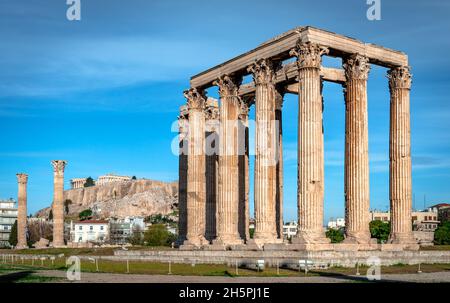 Die Ruinen des Tempels des olympischen Zeus. Es gibt 16 überlebende Säulen, von denen eine auf dem Boden liegt. Akropolis ist im Hintergrund. Stockfoto