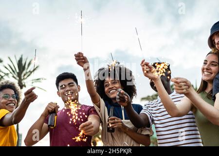 Gruppe von multirassischen Freunden, die im Freien lachen und feiern, funkelt Stockfoto