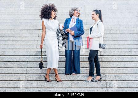 Drei Geschäftsfrauen lachen, während sie auf der Treppe stehen Stockfoto
