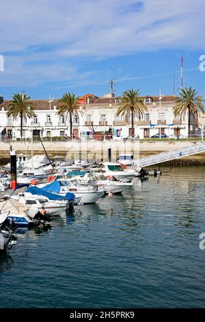 Jachten und Boote, die in der Marina mit Gebäuden am Wasser entlang der Avenida da Republica auf der Rückseite, Vila Real de Santo Antonio, Portugal, festgemacht sind. Stockfoto