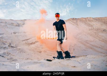 Extremer Absand auf Snowboard in der Wüste. Männlicher Snowboarder auf Dünen. Stockfoto