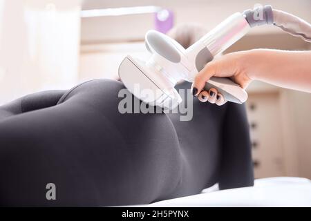 Die Frau erhält eine Flüssiggasmassage, um Cellulite aus ihrem Körper zu entfernen und die Beine zu heben. Konzept-Beauty-Therapie im Spa-Salon. Stockfoto