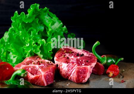 Zwei klassische frische Ribeye Steak auf Stein mit Kräutern Pfefferkörner über grauen Stein Oberfläche Hintergrund Draufsicht. Essen Stockfoto