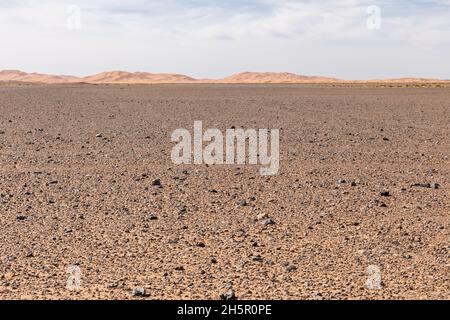 Verlassene Steinwüste vor den Sanddünen von Erg Chebbi im Vordergrund Stockfoto