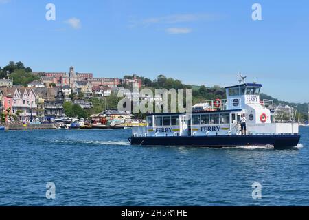 Die Passagierfähre „Kingswear Princess“ überquert den Fluss Dart von Dartmouth nach Kingswear. Die imposante alte Marine-Hochschule ist auf einem Hügel hinter dem Hotel zu sehen. Stockfoto