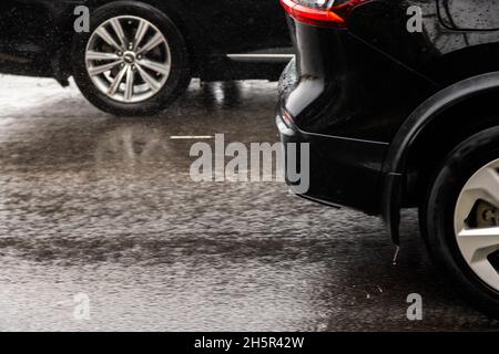 Zwei schwarze Autos fahren auf nasser herbstlicher Asphaltstraße Stockfoto