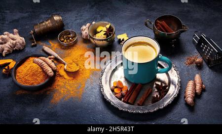 Gesunde goldene Kurkuma-Milch auf dunklem Hintergrund. Traditionelles indisches Getränk. Stockfoto