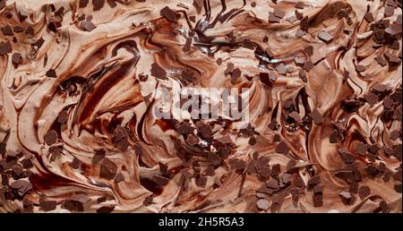 Leckere italienische Spezialität cremiges Schokoladeneis oder -Eis mit Schokoladenflocken in einem hautnahen strukturierten Hintergrund mit Wirbelmuster Stockfoto