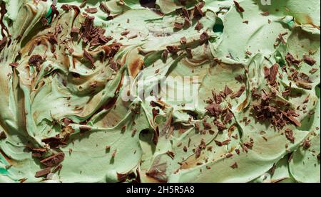 Minze, japanischer grüner Tee oder Matcha-Eis mit Schokoladenflocken in einer strukturierten, wirbelnden Hintergrundstruktur, die sich auf der Oberfläche des Dessertes befindet Stockfoto