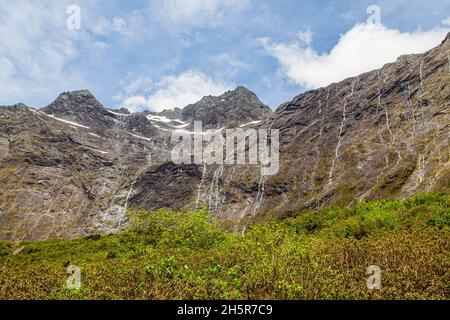 Eine Wand aus kleinen Wasserfällen von steilen Klippen auf dem Weg nach Fiordland. Neuseeland Stockfoto