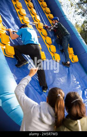 Freunde klettern auf aufblasbare Rutsche im Vergnügungspark Stockfoto