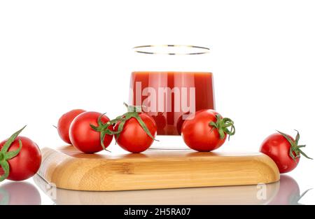 Eine Glastasse mit Tomatensaft und mehreren Tomaten auf einem Bambustablett, Nahaufnahme, isoliert auf Weiß. Stockfoto