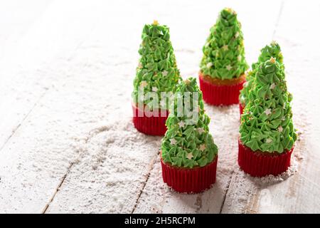 Weihnachtsbaum Cupcakes auf Schnee Holztisch Stockfoto