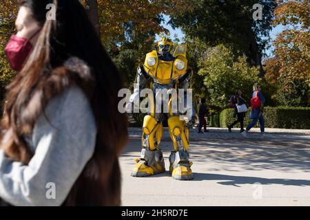 Madrid, Spanien - 09. Nov 2021: Ein Straßenkünstler, der als Bumblebee von den Transformers gekleidet ist, begrüßt die Kinder und bittet um Almosen im Retiro-Park Stockfoto