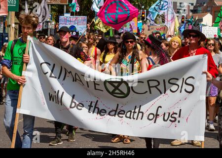 Straßenfoto einer großen Gruppe von Demonstranten bei einem Protest gegen den Klimawandel, der mit einer Samba-Band durch die Straßen einer Stadt ging Stockfoto