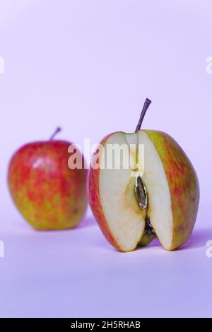 Vertikale Aufnahme von gespaltenen Äpfeln auf einem rosa Hintergrund Stockfoto