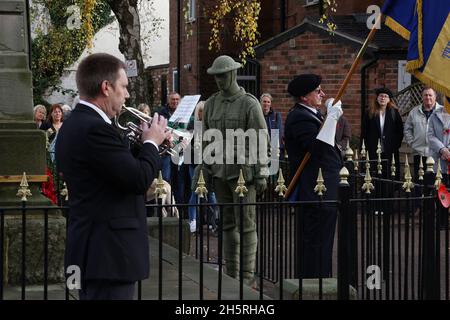 Syston, Leicestershire, Großbritannien. November 2021. Der letzte Beitrag wird während der waffenstillstandsfeiern im Syston war Memorial in der Nähe eines lebensgroßen gestrickten Soldaten gespielt. Credit Darren Staples/Alamy Live News. Stockfoto