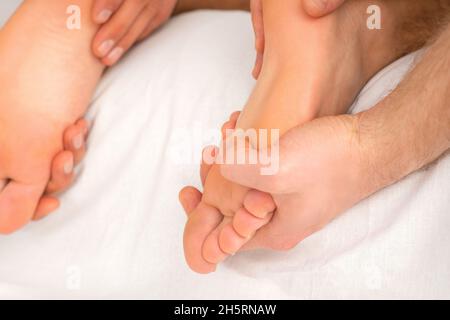 Entspannende Doppelmassage auf den weiblichen Füßen durch zwei Masseure im Spa-Salon Stockfoto