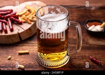 Ein Glas Bier und Snacks auf einem Holzhintergrund. Stockfoto