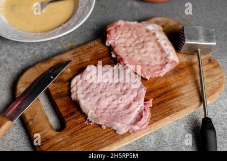 Zwei Stücke geschlagenen Fleisches auf einem Schneidebrett. Kochen von Schweinekoteletts. Stockfoto