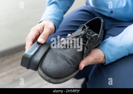 Hand Polieren schwarzen Herrenstiefel. Ein Geschäftsmann reinigt seine schwarzen Schuhe mit einem Schwamm. Stockfoto