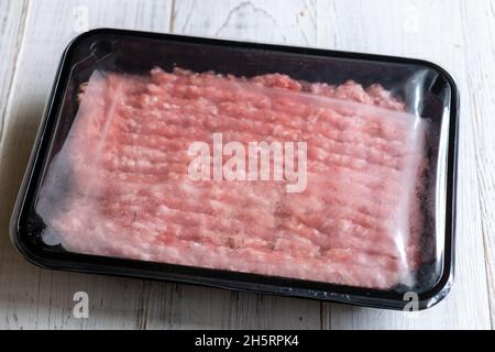 Hackfleisch in Kunststoffverpackung auf hellem Holzhintergrund. Stockfoto