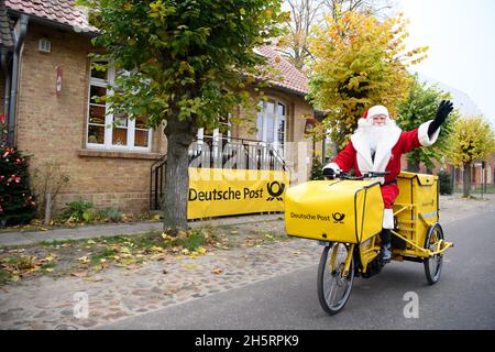 11. November 2021, Brandenburg, Fürstenberg/Havel/OT Himmelpfort: Der Weihnachtsmann sitzt winkend auf seinem Fahrrad, nachdem er bei der Weihnachtspost angekommen ist. Der Weihnachtsmann plant, jedes Wochenende bis Heiligabend von Freitag bis Sonntag in seinem Weihnachtspostamt zu sein. Während dieser Zeit kann er durch das Fenster gesehen werden, das die E-Mail beantwortet. Aufgrund der anhaltenden Corona-Infektionsgefahr ist sein weihnachtlich geschmücktes Büro in diesem Jahr jedoch nicht für Besucher geöffnet. Foto: Soeren Sache/dpa Stockfoto