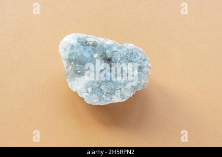 Blauer celestine Kristallstein mineralischer Edelstein. Natürliche, azurblaue, raue Celestine-Kristalle, Cluster auf beigem Hintergrund, Nahaufnahme. Draufsicht Stockfoto