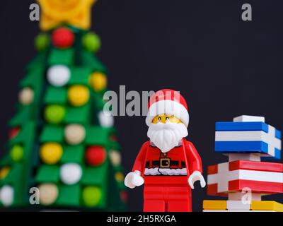 Tambow, Russische Föderation - 10. November 2021 Lego Santa Claus Minifigur mit Geschenken in seiner Nähe, die neben einem weihnachtsbaum stehen. Nahaufnahme. Stockfoto