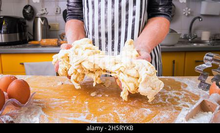 Schlechter Teig. Unerfahrene ungeschickte Frau, die in einer Schürze kocht, hält erfolglosen klebrigen Teig in ihren Händen. Сoncept des schlechten Kochens. Stockfoto