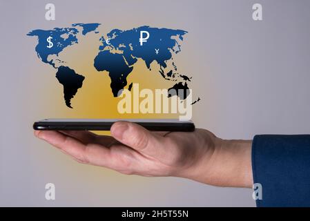 Das Telefon und die Karte des Planeten Erde als Symbol mit Währungszeichen verschiedener Länder der Welt. Das Konzept der Entwicklung des wo Stockfoto
