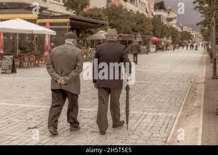 Foto im Vintage-Stil von zwei elegant gekleideten älteren Herren bei einem Spaziergang am frühen Abend in berat albanien Stockfoto