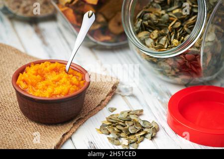 Kürbiskerne in einem Glasgefäß auf einem weißen Holzbrett trocknen Stockfoto