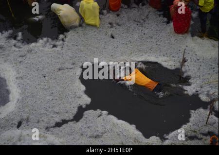 Neu-Delhi, Indien. November 2021. Giftiger Schaum schwimmt auf der Oberfläche des verschmutzten Yamuna-Flusses, während hinduistische Anhänger nach dem Baden als Teil der Rituale am Ende des viertägigen Festivals „Chhath Puja“ am Donnerstag, dem 11. November 2021, in Neu Delhi, Indien, beten. Das alte hinduistische Fest, das dem sonnengott gewidmet ist, wird für das Wohlergehen, die Entwicklung und den Wohlstand der Familienmitglieder gefeiert. Foto von Abhishek/UPI Credit: UPI/Alamy Live News Stockfoto