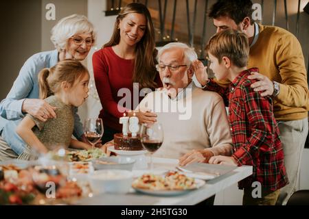Glückliche Familie feiert Großvater Geburtstag mit Kuchen und Kerzen zu Hause Stockfoto
