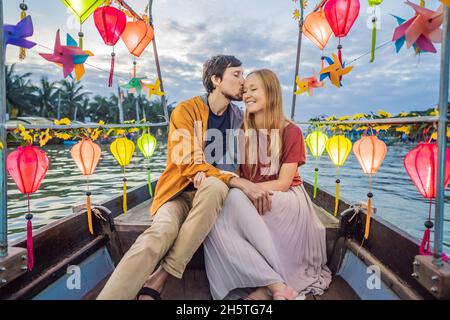 Ein glückliches Paar von Reisenden fährt auf einem Nationalboot auf dem Hintergrund der alten Stadt Hoi in Vietnam. Vietnam öffnet sich nach der Quarantäne wieder für Touristen Stockfoto