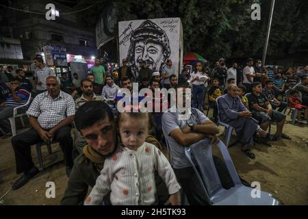 Palästinenser in der Nähe eines Wandbildes, das den verstorbenen palästinensischen Führer Yasser Arafat am 11. November 2021 in Rafah im südlichen Gazastreifen zeigt. Stockfoto