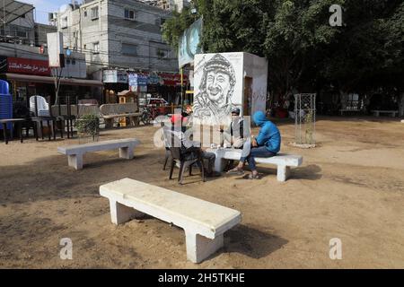 Palästinenser in der Nähe eines Wandbildes, das den verstorbenen palästinensischen Führer Yasser Arafat am 11. November 2021 in Rafah im südlichen Gazastreifen zeigt. Stockfoto
