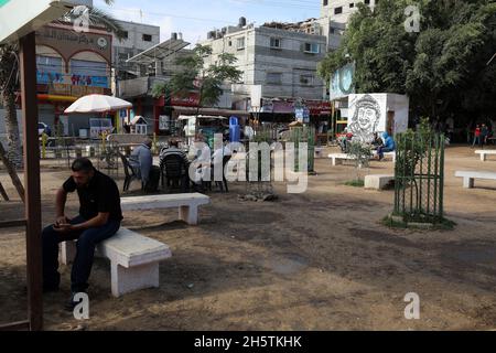 Palästinenser in der Nähe eines Wandbildes, das den verstorbenen palästinensischen Führer Yasser Arafat am 11. November 2021 in Rafah im südlichen Gazastreifen zeigt. Stockfoto