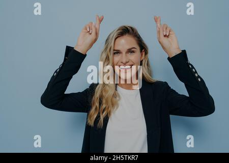 Aufgeregt blonde Mädchen mit gekreuzten Fingern wünschen Stockfoto