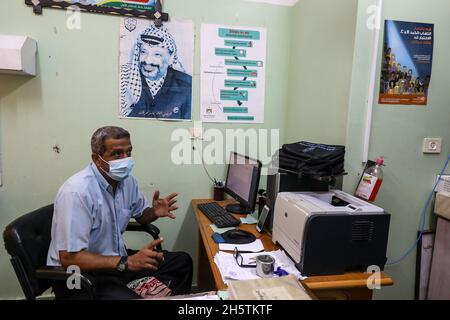 Palästinenser in der Nähe eines Wandbildes, das den verstorbenen palästinensischen Führer Yasser Arafat am 11. November 2021 in Rafah im südlichen Gazastreifen zeigt. Stockfoto