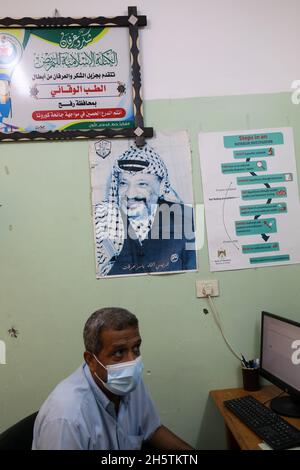 Palästinenser in der Nähe eines Wandbildes, das den verstorbenen palästinensischen Führer Yasser Arafat am 11. November 2021 in Rafah im südlichen Gazastreifen zeigt. Stockfoto